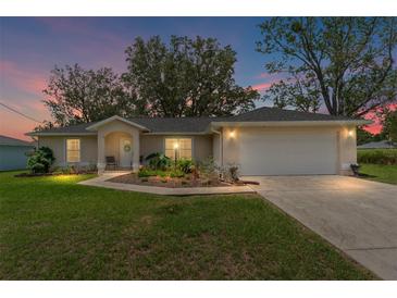Charming single-story home with a well-manicured lawn and a two-car garage at twilight at 106 Pine Trce, Ocala, FL 34472