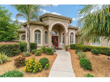 Stunning single-story home featuring a charming red door, lush landscaping, and inviting curb appeal at 3986 Se 43Rd Cir, Ocala, FL 34480