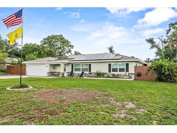 Charming single-story home with a well-manicured lawn, solar panels, and a welcoming front porch at 460 E Haines Blvd, Lake Alfred, FL 33850