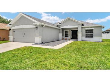 Well maintained gray home featuring a two car garage and inviting front yard at 5133 Sw 41St Pl, Ocala, FL 34474