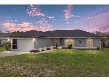 Charming single story home with a well manicured lawn, complemented by a two car garage and lovely sunset skies at 63 Walnut Crse, Ocala, FL 34480