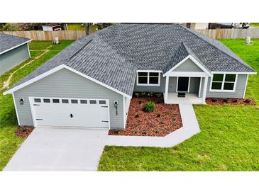 An aerial of a single-story home with a two-car garage, manicured lawn, and tasteful landscaping at 8289 Se 159Th Ln, Summerfield, FL 34491