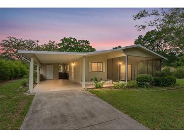 Charming single-story home with a carport, screened porch, and well-maintained landscaping under a colorful sky at 10012 Sw 88Th Ct, Ocala, FL 34481