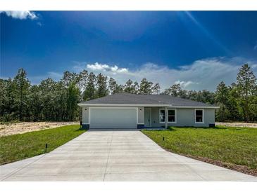 Charming single-story home featuring a two-car garage and well-maintained front lawn on a sunny day at 1390 Sw Obee Ridge Rd, Dunnellon, FL 34431