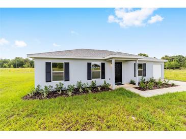 Charming single-story home with gray exterior, black shutters, and lush landscaping at 14885 Sw 23Rd Pl, Ocala, FL 34481