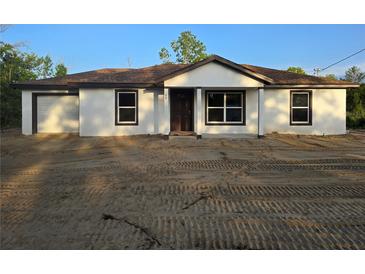Newly constructed single-story home featuring white exterior, brown trim, and an attached garage at 20 Malauka Trail Crse, Ocklawaha, FL 32179