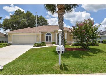 Well-maintained single-story home featuring a lush front lawn with a palm tree and a two car garage at 2478 Nw 50Th Ave, Ocala, FL 34482