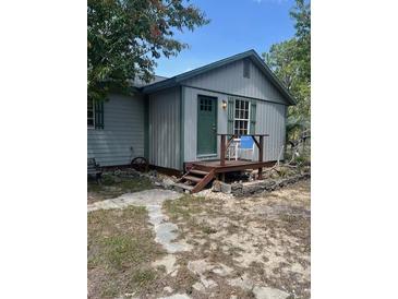 Charming home exterior with green door and trim, complemented by a cozy front porch at 1013 Nw Mandrake Dr, Dunnellon, FL 34431