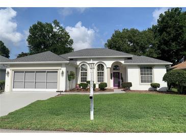 Charming single-story home with well-manicured lawn, a purple door, and a two car garage at 11605 Sw 69Th Cir, Ocala, FL 34476