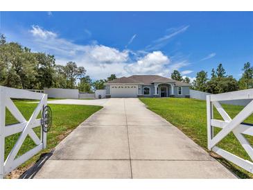 Charming single-story home with a long driveway and a well-manicured lawn, under a bright blue sky at 12392 Sw 85 Pl, Dunnellon, FL 34432