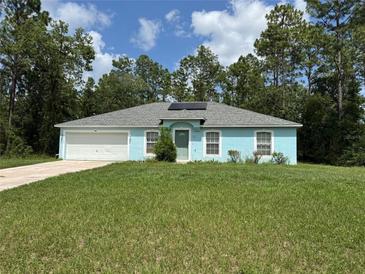 Charming single-story home featuring an attached garage, a well-maintained lawn, and mature trees at 13155 Sw 73 Ave, Ocala, FL 34473