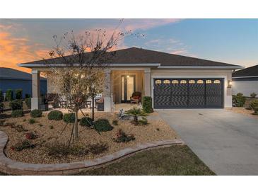 Charming single-story home featuring a landscaped front yard, covered porch, and a two-car garage with decorative windows at 8878 Sw 103Rd Cir, Ocala, FL 34481