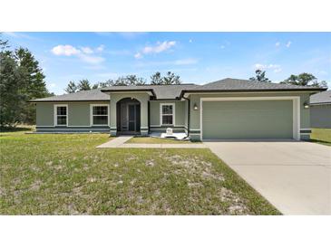 Inviting single-story home with a well-maintained lawn, two car garage, and pleasing light green paint at 15994 Sw 55Th Avenue Rd, Ocala, FL 34473