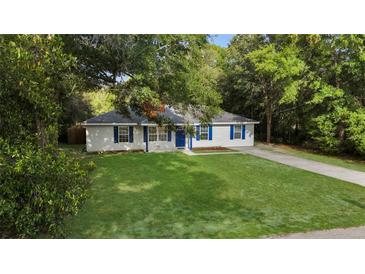 Charming one-story home with a well-manicured lawn, blue shutters, and mature trees at 2263 Moines Ct, Dunnellon, FL 34431