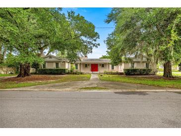 Charming single-story home with mature trees and a vibrant red front door at 4025 Ne 18Th St, Ocala, FL 34470