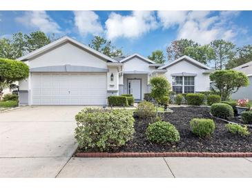 Charming one-story home featuring a manicured front yard with lush landscaping and a two-car garage at 5151 Sw 39Th St, Ocala, FL 34474