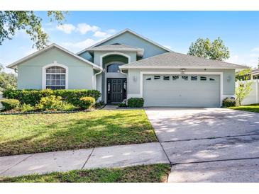 Charming home with a well-manicured lawn, mature landscaping, and an attached two-car garage at 1584 Silhouette Dr, Clermont, FL 34711