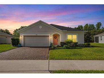 Charming single-story home with a brick driveway, manicured lawn, and a decorative wreath on the front door at 358 Irving Bend Dr, Groveland, FL 34736