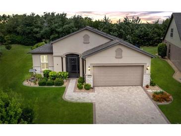 Charming single-story home featuring a manicured lawn, paver driveway, and neutral stucco exterior at 7839 Sw 97Th Cir, Ocala, FL 34481