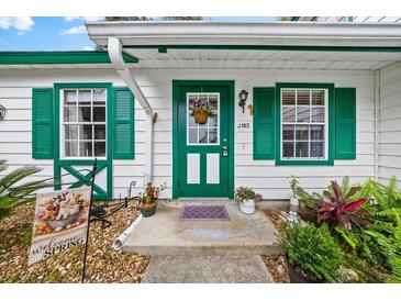 Inviting front door with green trim, a hanging flower basket, and decorative windows add charm to the entrance at 7961 Midway Drive Ter # J102, Ocala, FL 34472