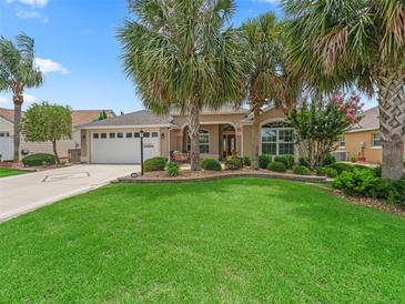 Inviting home featuring lush landscaping, mature palm trees, and a well-manicured lawn at 1266 James Island St, The Villages, FL 32162