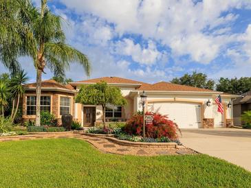 Charming single-story home features stone accents, a well-manicured lawn, mature palms and appealing landscaping at 1953 Hartford Path, The Villages, FL 32162