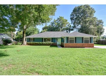Charming single-story home with a well-manicured lawn, mature trees, and appealing blue exterior at 2855 Se 38Th St, Ocala, FL 34480