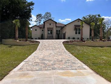 Stunning single-Gathering home featuring a stone facade, manicured lawn, and a brick driveway leading to the residence at 5034 Nw 75Th Ave, Ocala, FL 34482