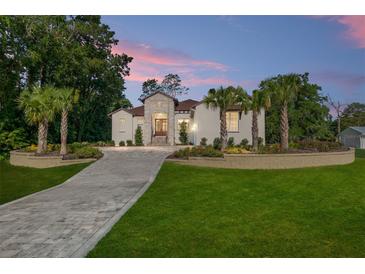 Elegant stucco home featuring a stone facade, paved driveway, and a meticulously landscaped front yard with palm trees at 5034 Nw 75Th Ave, Ocala, FL 34482