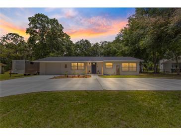 Charming single-story home with a spacious driveway and well-maintained lawn at sunset at 802 Ne 39Th Ct, Ocala, FL 34470