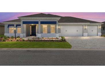 Charming home featuring a three-car garage and stylish blue accents on the front facade at 10045 Sw 82Nd Place Rd, Ocala, FL 34481