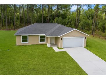 Beautiful tan home features a well-maintained lawn, attached two car garage, and a neutral color scheme at 1083 Sw Winding Hills Rd, Dunnellon, FL 34431