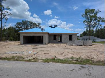 Unfinished concrete block home with blue roofing being built in a sunny, undeveloped neighborhood at 13322 Sw 85 Cir, Ocala, FL 34473
