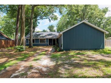 Charming home featuring a blue exterior, lush landscaping, and mature trees for added privacy and curb appeal at 1841 Ne 38Th St, Ocala, FL 34479