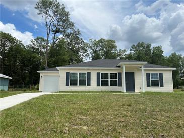 Charming single-story home featuring a well-manicured lawn, attached garage, and classic exterior at 185 Malauka Loop, Ocklawaha, FL 32179