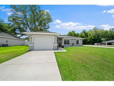 Charming single-story home with a well-manicured lawn and attached two-car garage, perfect for suburban living at 3094 Se 144Th Pl, Summerfield, FL 34491