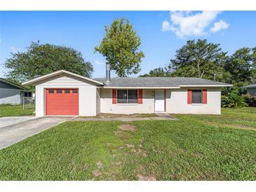 Charming single-story home with a well-maintained lawn, red garage door, and red window shutters at 3428 Ne 17Th Ter, Ocala, FL 34479