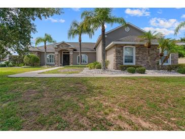Charming single-story home featuring stone accents, a well-manicured lawn, and tropical palm trees at 4731 Se 34Th St, Ocala, FL 34480
