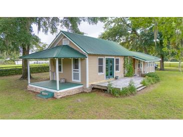 Charming home featuring a metal roof, a covered front porch and a wooden deck surrounded by a spacious green lawn at 1501 Ne 97Th Street Rd, Anthony, FL 32617