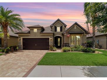 Charming home featuring a well-manicured lawn, brick driveway and two-car garage at dusk at 7814 Sw 97Th Cir, Ocala, FL 34481