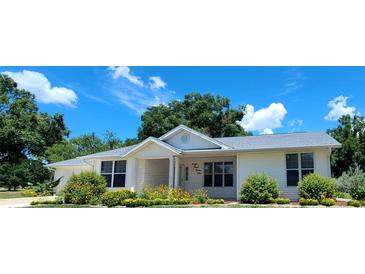 Inviting single-story home with manicured front lawn and beautiful flower beds under a blue sky at 8771 Sw 115Th St, Ocala, FL 34481