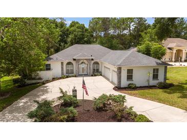Stunning single-story home with manicured landscaping, a circular driveway, and an American flag at 9213 Sw 197Th Cir, Dunnellon, FL 34432