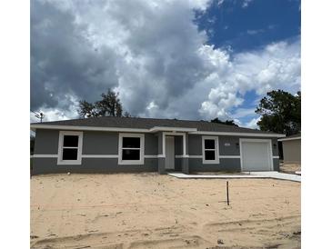 Charming one-story home with a gray exterior, white trim, and a well-manicured lawn at 10385 Se 125Th Ln, Belleview, FL 34420