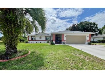 Charming single-story home with a well-maintained lawn and a two car garage with a palm tree in the front yard at 10459 Sw 62Nd Ct, Ocala, FL 34476