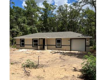New construction home with neutral paint, dark trim, and attached one-car garage in a wooded setting at 20769 Sw Oriole Dr, Dunnellon, FL 34431