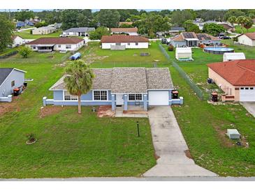 Charming single-story home featuring a well-manicured lawn, attached garage, and welcoming light blue painted facade at 316 Oak Track Dr, Ocala, FL 34472