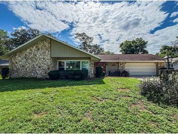 Charming stone-accented home featuring a well-maintained lawn, red front door and attached two-car garage at 3545 Se 24Th Ave, Ocala, FL 34471