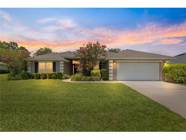 Inviting home with lush lawn, mature landscaping, and attached two car garage at 8 Diamond Club Rd, Ocala, FL 34472