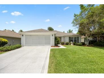 Charming single-story home with a well-manicured lawn and a two-car garage at 11728 Se 91St Cir, Summerfield, FL 34491