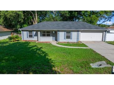 Charming single-story home with a well-manicured lawn, blue shutters, and an attached garage at 26 Hemlock Terrace Dr, Ocala, FL 34472
